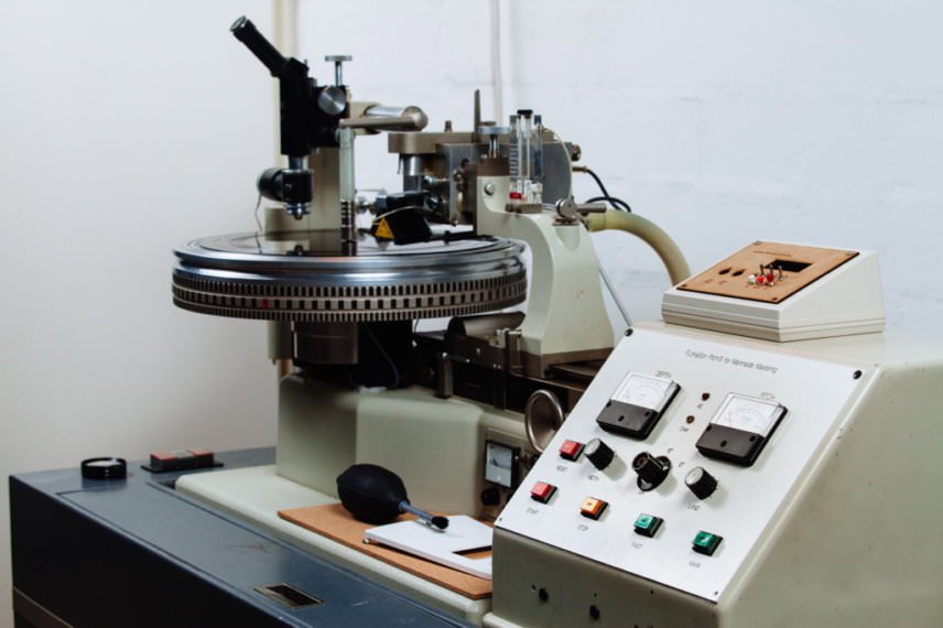 "Close-up of a Neumann vinyl cutting lathe, featuring the turntable and control panel used in the process of mastering vinyl records.