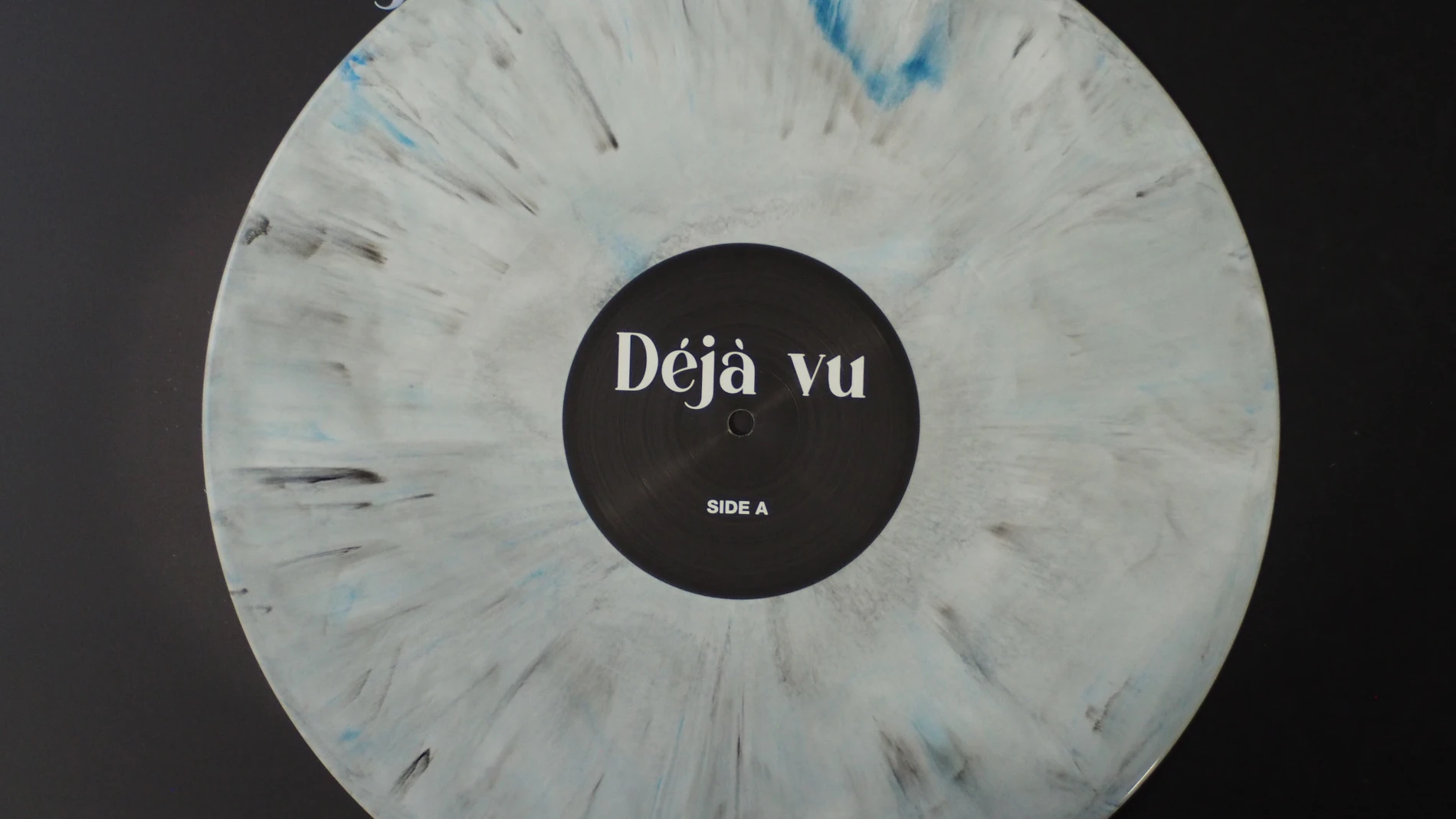 Top-down view of Augustina – Déjà Vu white marble vinyl with black center label.