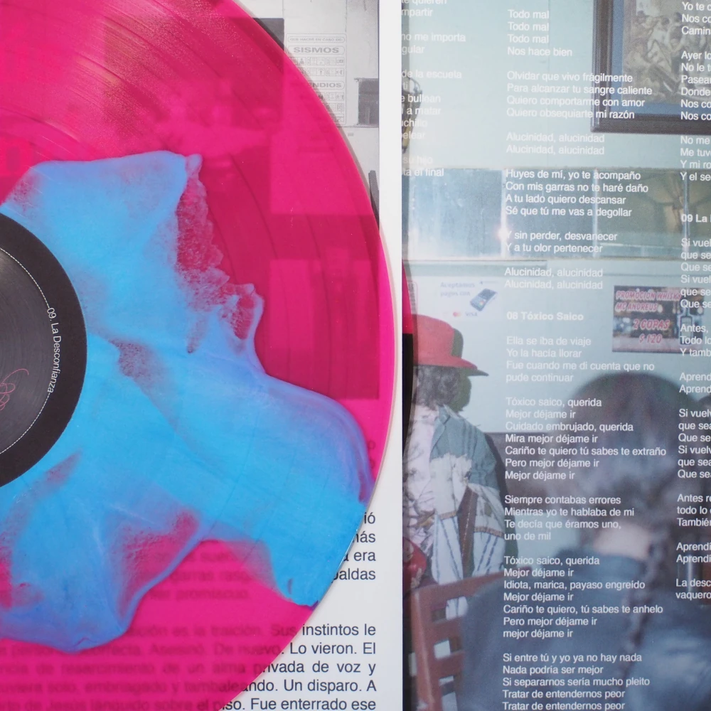 Transparent pink vinyl with blue splatter overlaying printed lyrics insert.