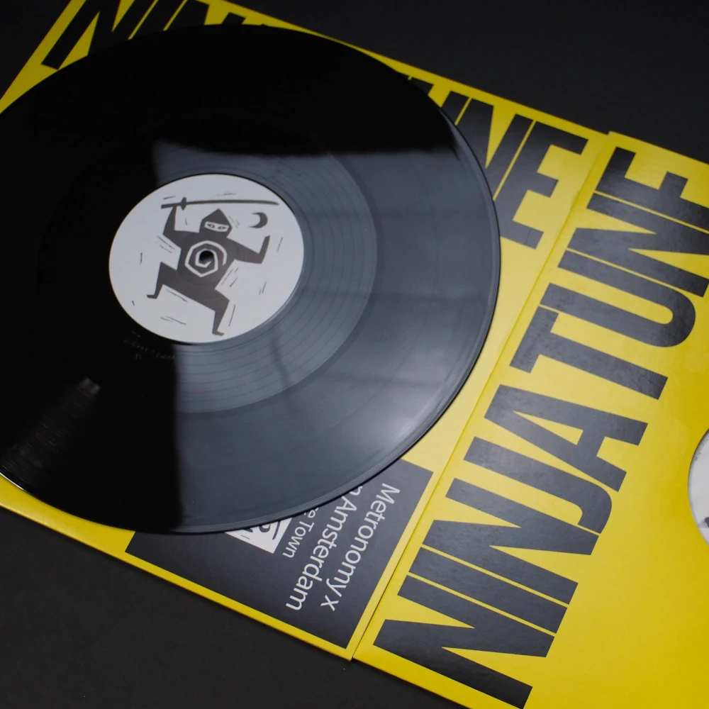 Black vinyl pulled halfway out of a yellow Ninja Tune jacket with logo label.
