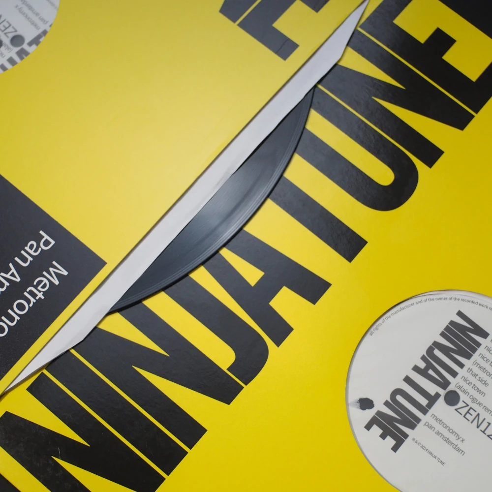 Close-up of Ninja Tune yellow sleeve with vinyl peeking from die-cut jacket.