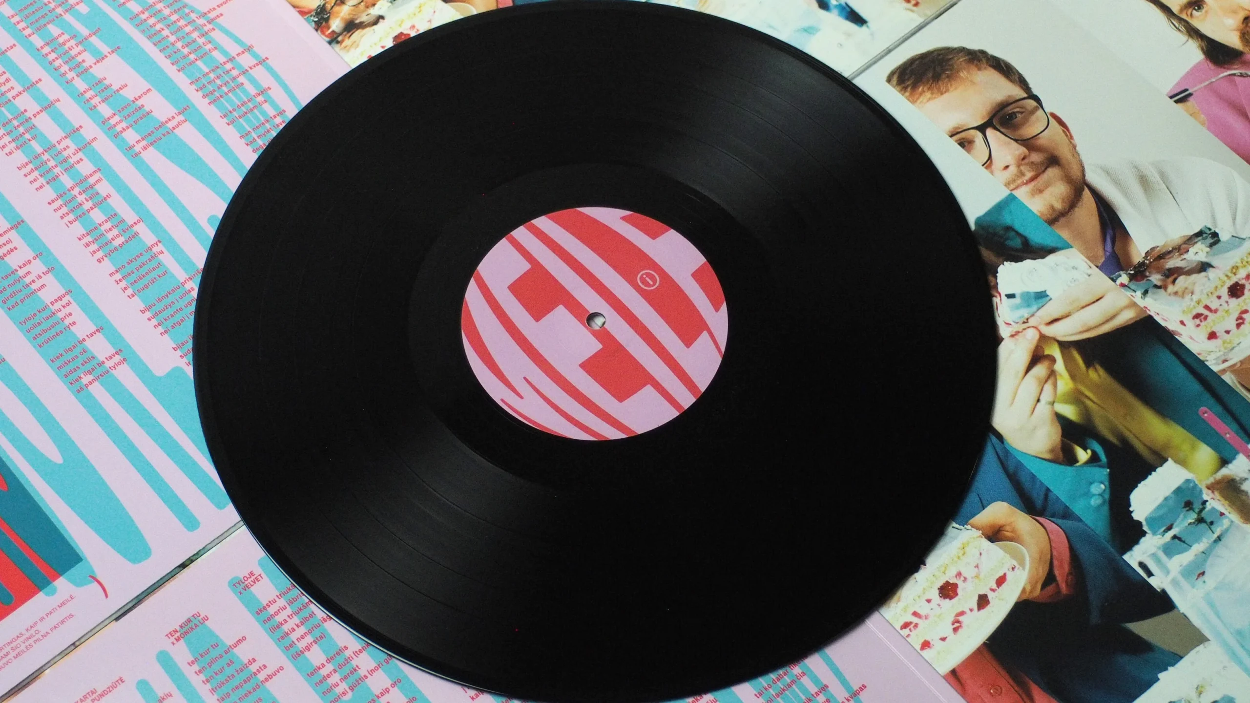 Black vinyl record laid on top of printed insert with lyrics and photos.