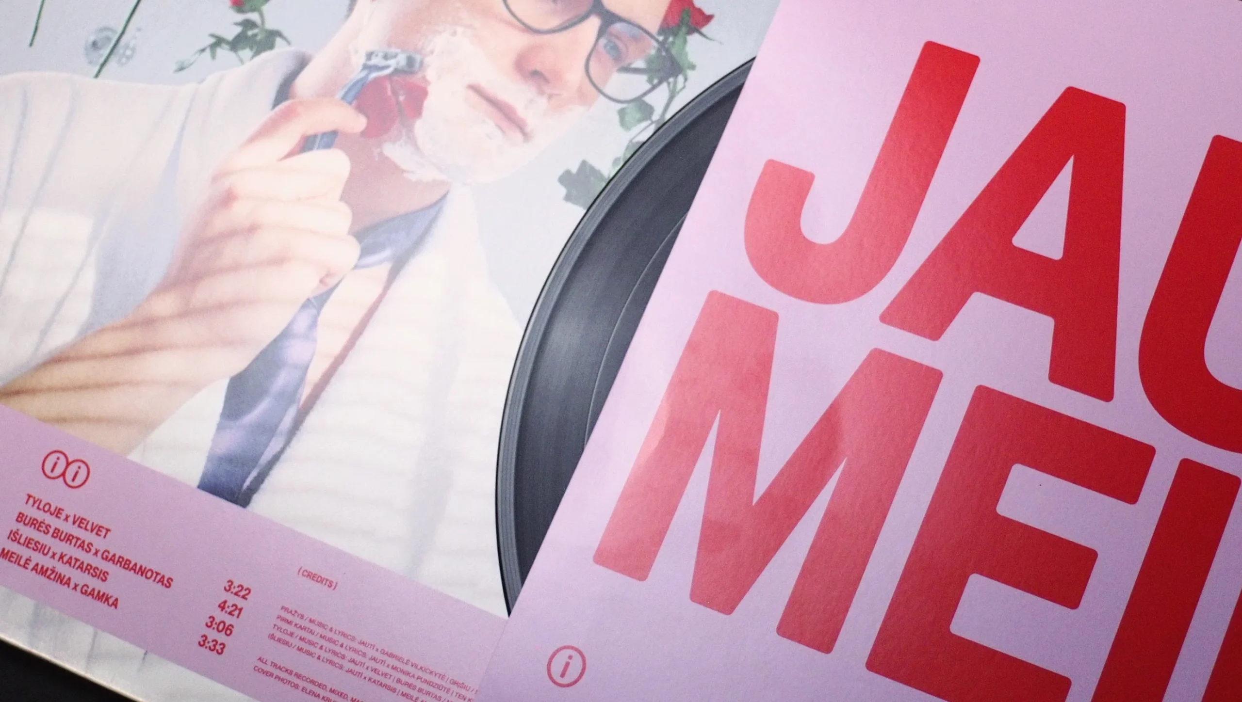 Black vinyl record peeking out from inside the bright cover.