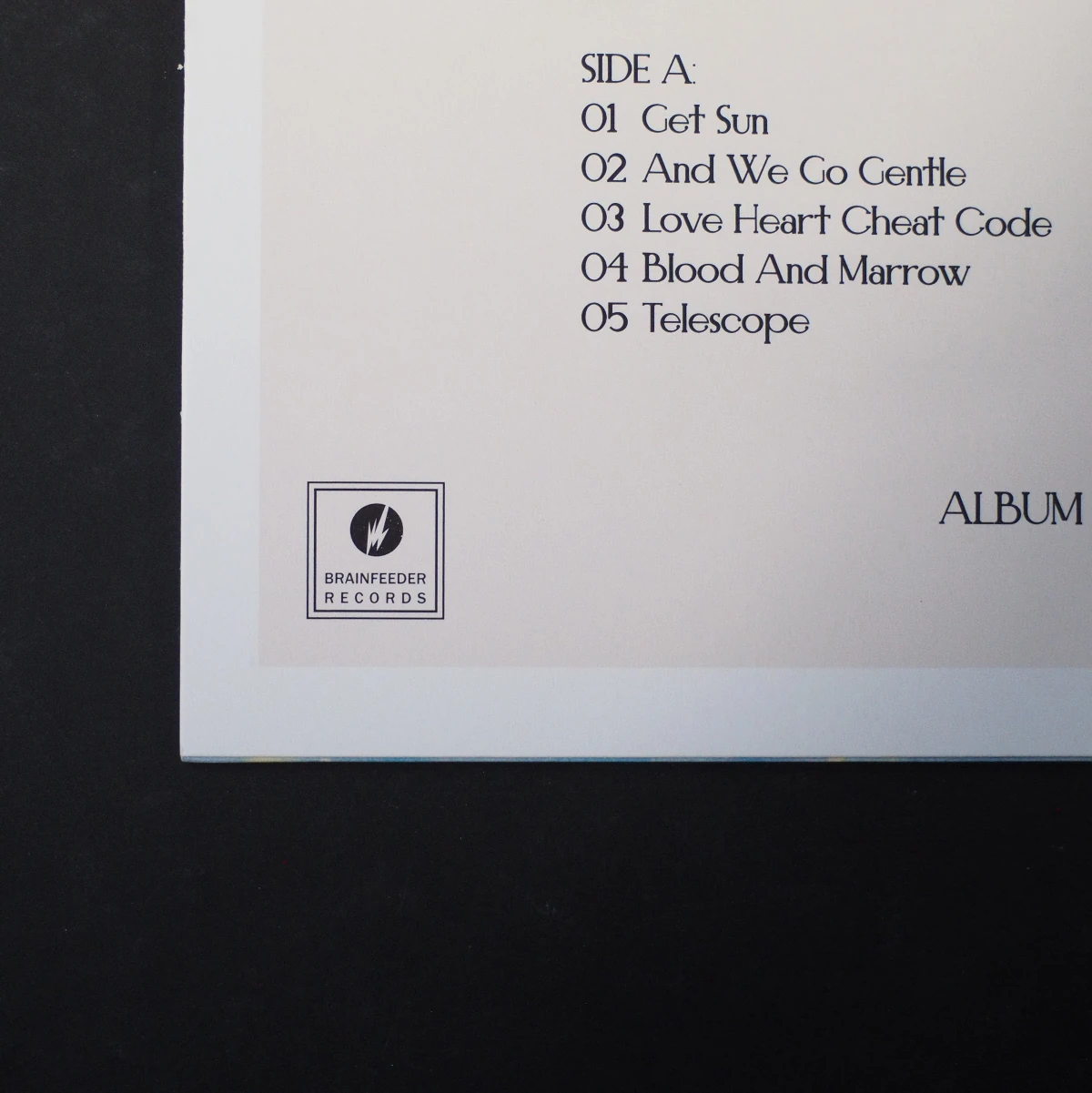 Back cover tracklist of Tres Leches with Brainfeeder logo.