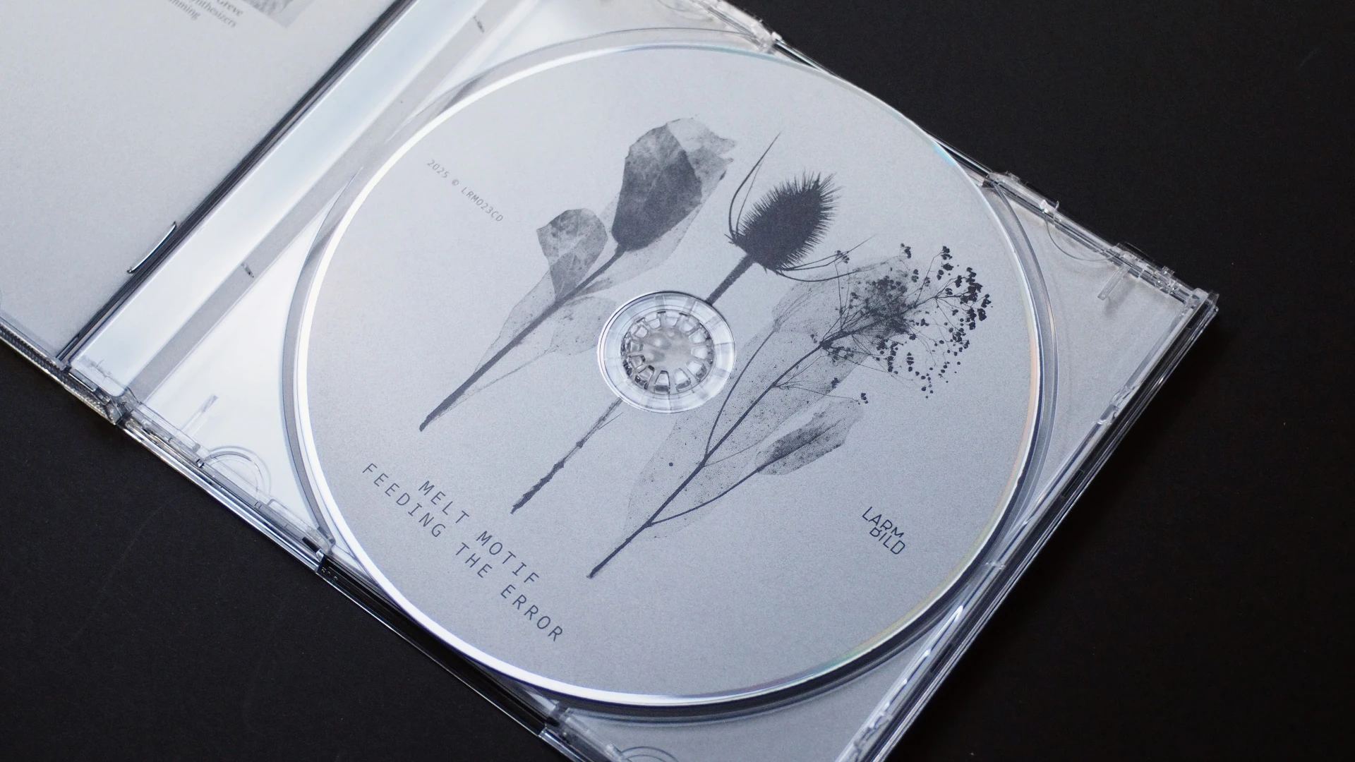 CD with botanical illustration inside a transparent jewel case, minimal grayscale print.