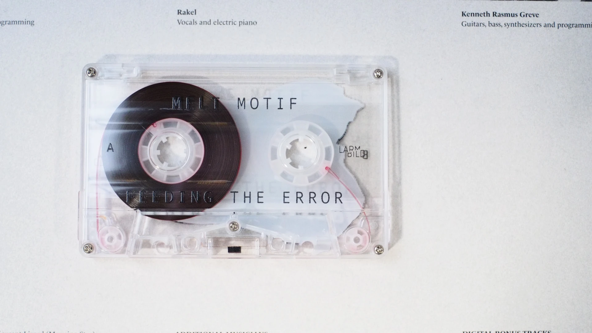 Clear cassette labeled “Melt Motif – Feeding The Error” with visible tape and clean type.